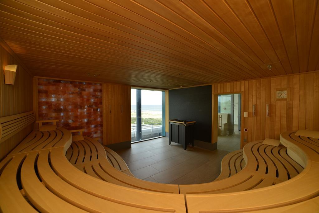 Hotel Neptun Rostock Exterior photo The image depicts a modern sauna interior. The walls are made of wood, contributing to a warm and natural atmosphere. The seating is arranged in a curved design, allowing for multiple people to relax comfortably. Large windows provide a view of the o