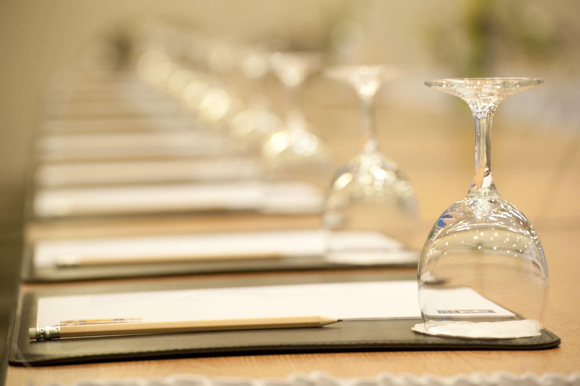 Hotel Neptun Rostock Exterior photo The photo shows a long table set for a meeting or event. It features neatly arranged place settings with white sheets of paper on dark folders. Each setting has an upside-down wine glass, creating a uniform and elegant appearance. Additionally, there